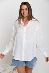 Woman wearing a white button-up shirt and denim shorts on a plain background
