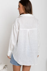 Woman wearing a white oversized shirt and denim shorts on a plain background