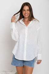 Woman wearing a white shirt and denim shorts on a plain background