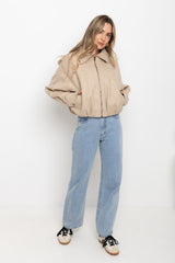 Woman wearing a beige jacket and blue jeans on a white background