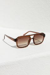 Brown sunglasses on a textured white surface