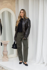 Eddie vegan leather jacket in chocolate brown, oversized bomber-style jacket with snap buttons, styled with a black tee and olive green barrel leg pants