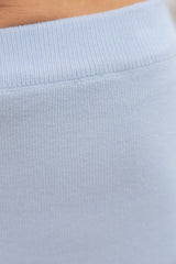 Close-up of a light blue ribbed knit fabric with a small portion of skin visible at the top edge.