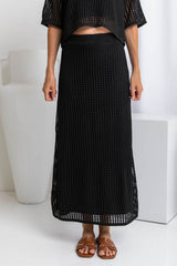 A model wearing a midi length black crochet knit skirt with a ribbed elastic waistband and fitted silhouette.