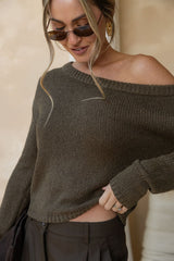 Woman wearing a brown off-shoulder sweater against a beige background