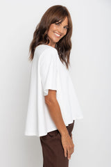 Woman wearing a white top and brown pants against a white background
