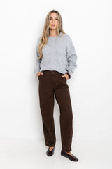 Woman wearing a gray sweater and brown pants on a white background