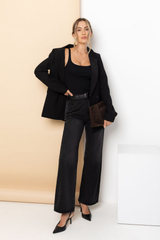 Woman in a black outfit standing against a white wall.