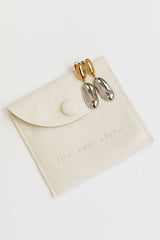 Pair of earrings on a white pouch with 'the self styler' branding.