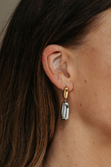 Close-up of an ear wearing a gold and silver earring with dark hair.