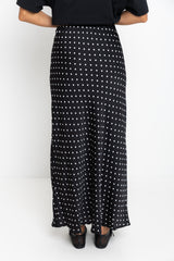 Person wearing a black and white polka dot skirt on a white background