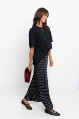 Woman wearing a black top and patterned skirt with a white background