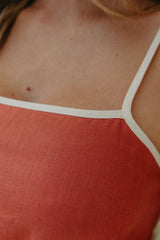 Close-up of a person wearing a red top with thin white straps.