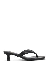 A single black leather thong sandal with a low kitten heel, shown in a side profile view against a solid white background.