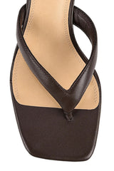 A close-up top-down view of a dark brown leather thong sandal with a square toe and a light beige insole, set against a plain white background.