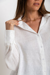 Woman wearing a white button-up shirt against a plain background