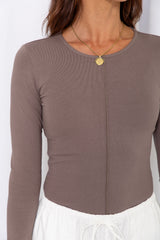 Woman wearing a taupe long-sleeve top with white drawstring pants, on a white background.