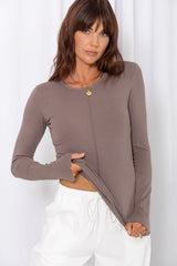 Woman wearing a taupe long-sleeve top with white drawstring pants, on a white background.