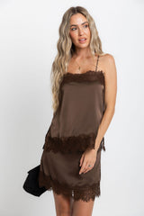 Woman wearing a brown slip dress with lace trim against a white background