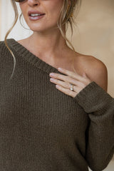 Woman wearing a brown off-shoulder sweater with a neutral background