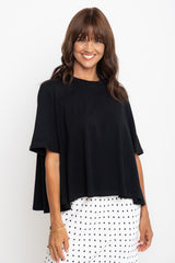 Woman wearing a black top and white polka dot skirt on a white background