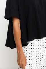 Person wearing a black outfit with a gold bracelet on a white background
