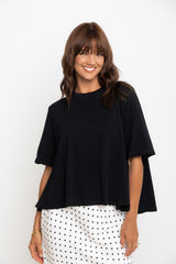 Woman wearing a black top and polka dot pants on a white background