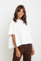 Woman wearing a white top and brown pants on a plain background