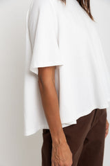 Person wearing a white top and brown pants against a plain background
