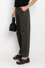 Person wearing olive green pants and black sandals, holding a black handbag on a white background