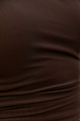 A close-up of dark brown textured fabric with soft folds and a fine woven pattern.