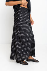Person wearing a black and white polka dot skirt on a white background
