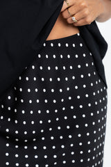 Black polka dot skirt with a close-up of a hand wearing a ring.