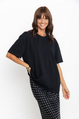 Woman wearing a black top and patterned pants on a white background