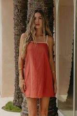 Woman in a coral dress standing next to a palm tree