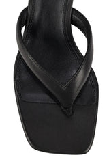 A close-up of a black leather thong sandal with a square toe, set against a plain white background.