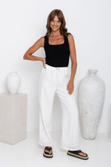 Willow straight-leg linen pants in white, drawstring waist trousers styled with a black tank top and platform flip-flop sandals