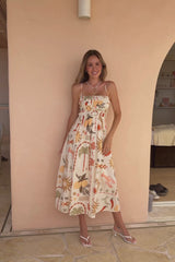 Woman in a floral dress standing by a beige wall